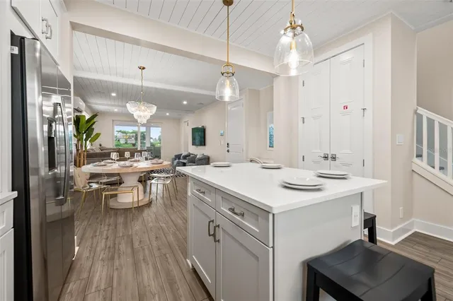 a kitchen with a sink dishwasher a stove a dining table and chairs with wooden floor