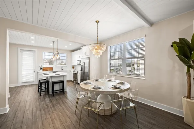 a dining room with wooden floor a chandelier a wooden table and chairs
