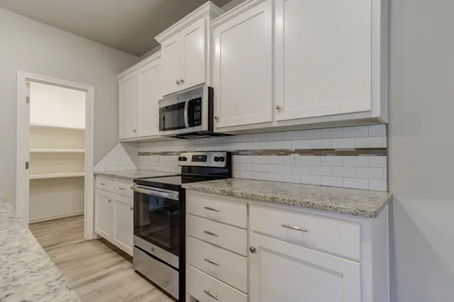a kitchen with granite countertop white cabinets and stainless steel appliances