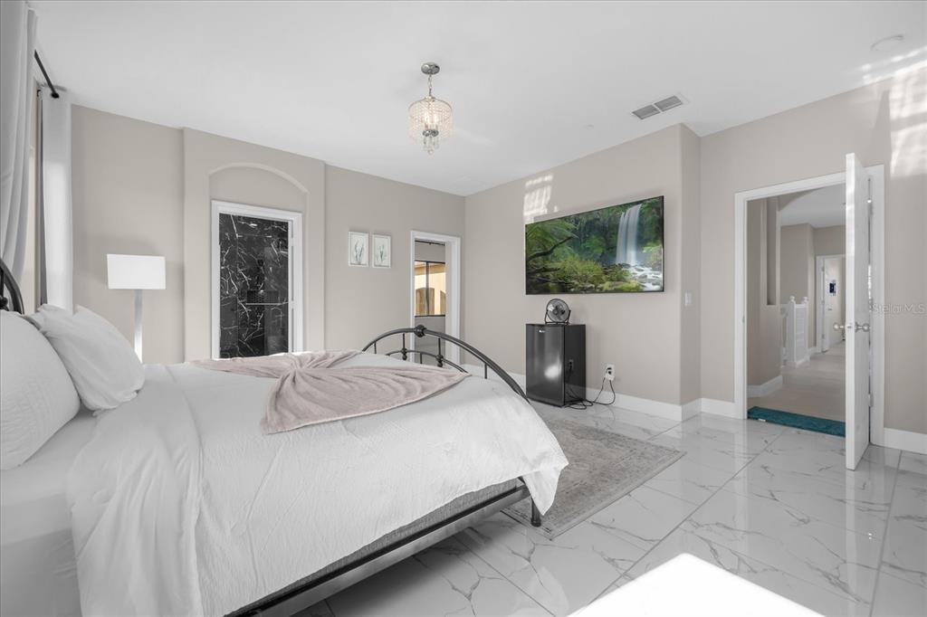 9657 Moss Rose Way Orlando, FL 32832 - Photo 13 of 33 a spacious bedroom with a bed and a flat screen television
