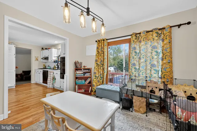 a open kitchen with stainless steel appliances granite countertop a refrigerator a sink dishwasher a dining table and chairs with wooden floor