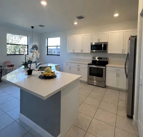 a kitchen with stainless steel appliances a sink a microwave a refrigerator and cabinets