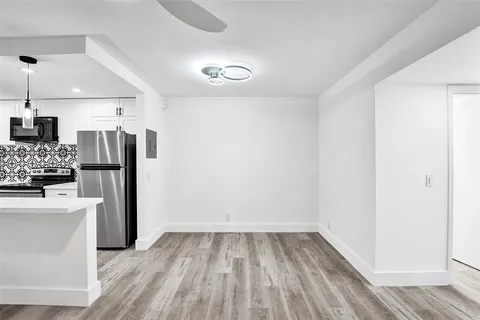 a view of a kitchen with refrigerator and wooden floor