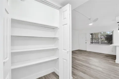 a view of an empty room with window and wooden floor
