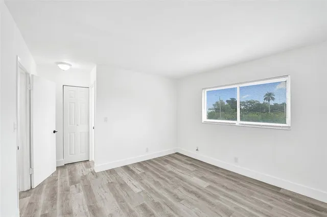 an empty room with wooden floor and window