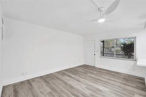 an empty room with wooden floor and window