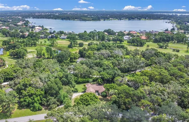 an aerial view of a houses with a yard and lake