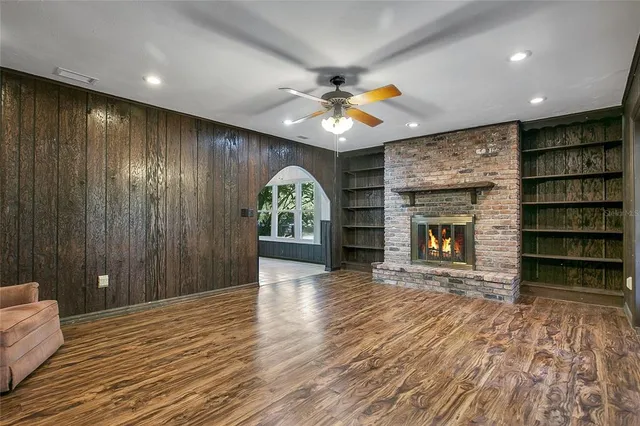an empty room with wooden floor fireplace and windows