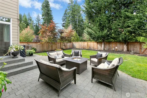 a view of a backyard with table and chairs potted plants and a large tree