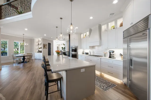 a kitchen with stainless steel appliances granite countertop a refrigerator a oven a sink a dining table and chairs with wooden floor