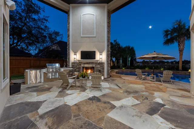 a view of a patio with a table and chairs under an umbrella with a fire pit and potted plants