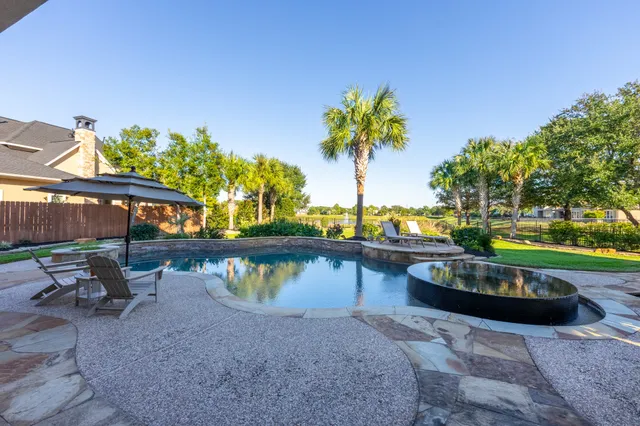 a view of a swimming pool with a patio and a yard