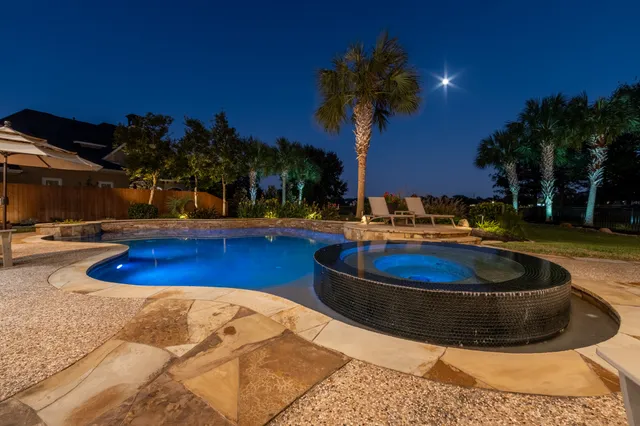 a swimming pool with outdoor seating yard and palm tree