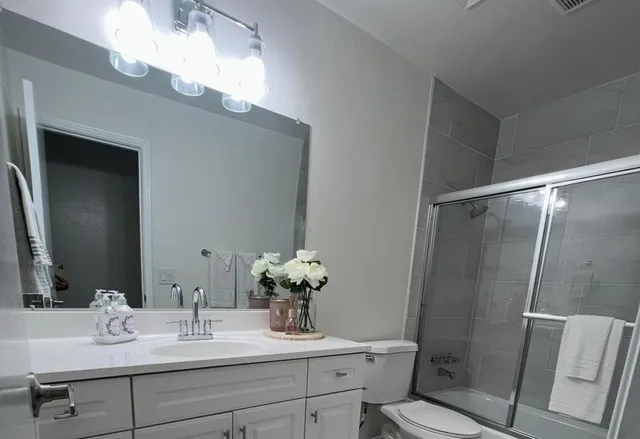 a bathroom with a granite countertop sink toilet and shower