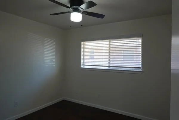 an empty room with a window and a fan