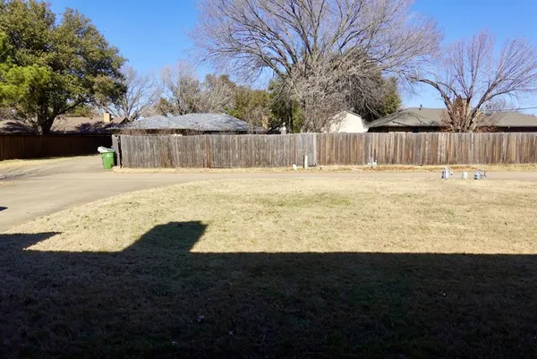 a view of a yard with wooden fence