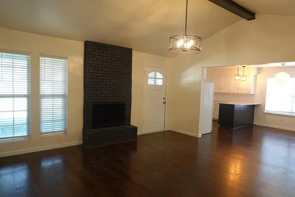 a view of a livingroom with wooden floor a ceiling fan and a kitchen space