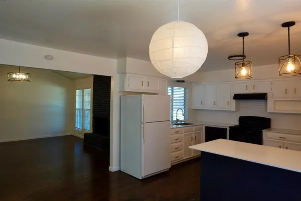 a kitchen with a refrigerator a stove and a wooden floor