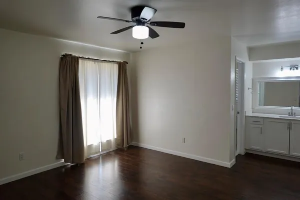 an empty room with wooden floor cabinet and windows