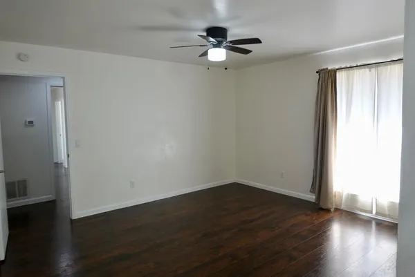 a view of an empty room with wooden floor and a window