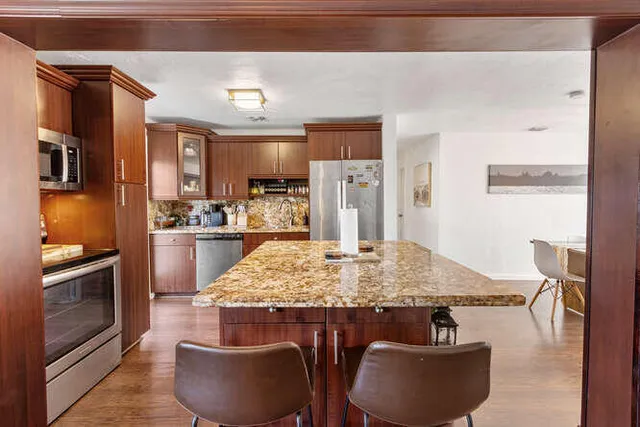 a kitchen with stainless steel appliances granite countertop a sink refrigerator and cabinets
