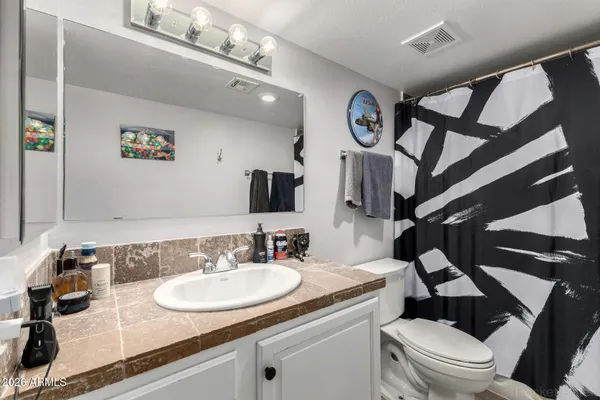 a bathroom with a granite countertop sink a toilet and a mirror