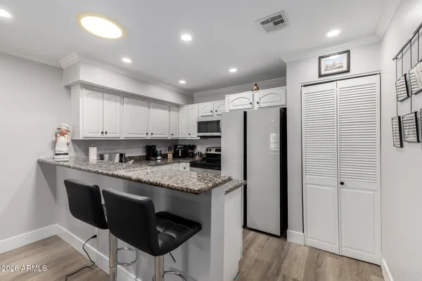 a kitchen with stainless steel appliances granite countertop a refrigerator a stove and a sink with wooden floor