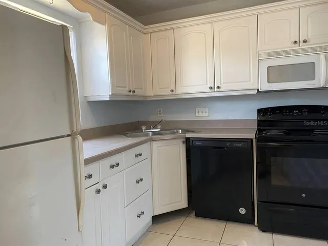 a kitchen with granite countertop white cabinets and stainless steel appliances