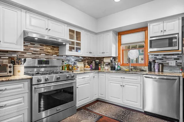 a kitchen with stainless steel appliances granite countertop a stove and white cabinets
