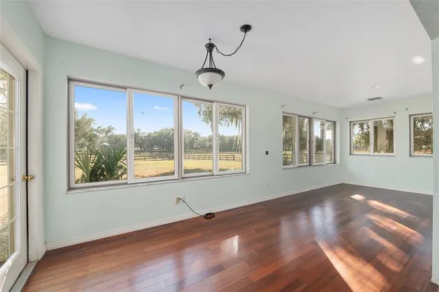 a view of an empty room with wooden floor and windows