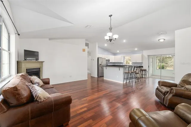 a living room with furniture kitchen view and a chandelier