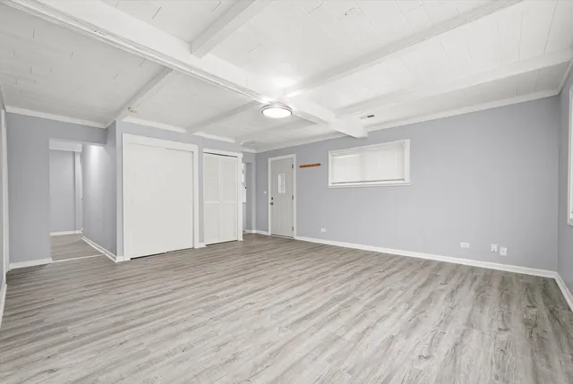 a view of an empty room with wooden floor and a ceiling fan