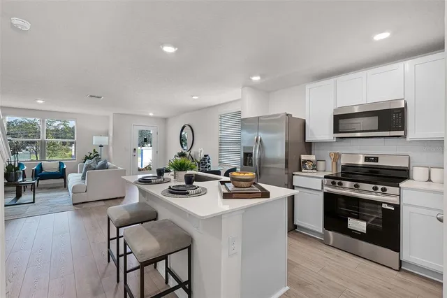 a living room with stainless steel appliances a kitchen island hardwood floor and a view of living room