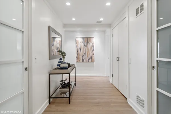 a hallway with wooden floor white walls and stairs