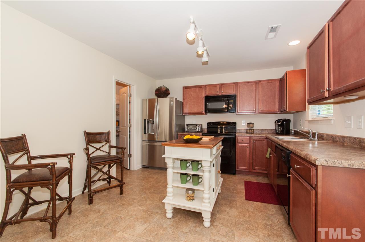6412 Flanking Lane Raleigh, NC 27610 - Photo 5 of 22 a kitchen with granite countertop a refrigerator stove a sink a dining table and chairs