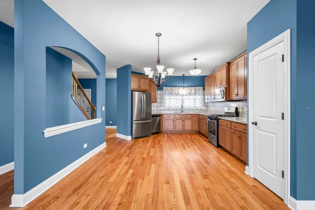 a large kitchen with stainless steel appliances granite countertop a stove a sink dishwasher and a refrigerator with wooden floor