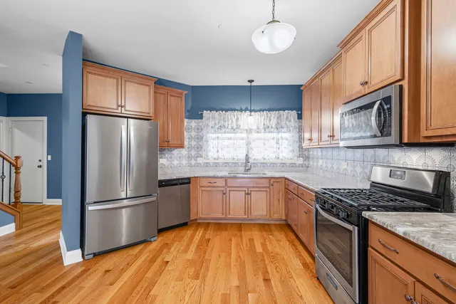 a kitchen with granite countertop stainless steel appliances a refrigerator cabinets and wooden floor