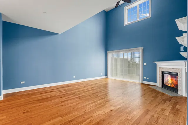 a view of an empty room with wooden floor and a fireplace