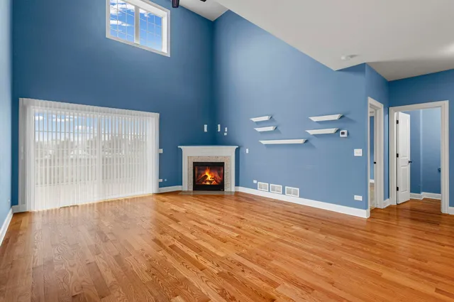 a view of an empty room with wooden floor and a fireplace