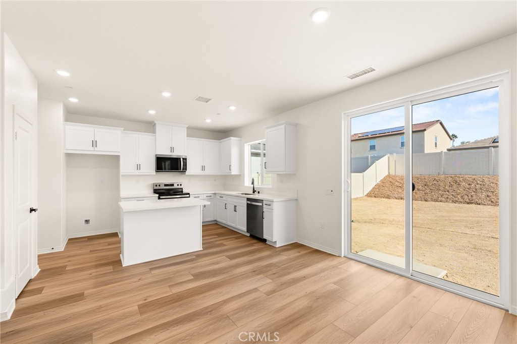 19434 Arenal Way Riverside, CA 92508 - Photo 5 of 25 a kitchen with white cabinets and stainless steel appliances