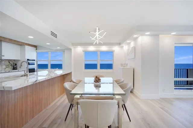 a kitchen with stainless steel appliances kitchen island granite countertop a table chairs in it and wooden floors