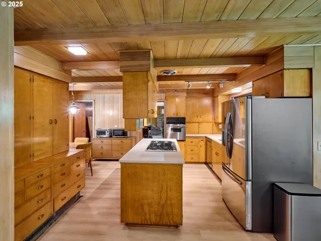 a dining hall with stainless steel appliances kitchen island granite countertop a refrigerator and a wooden cabinets