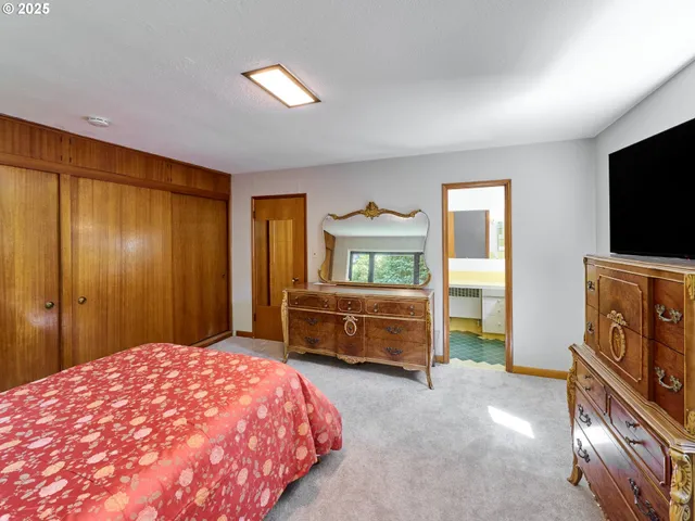 a bedroom with a bed and a flat tv screen on dresser