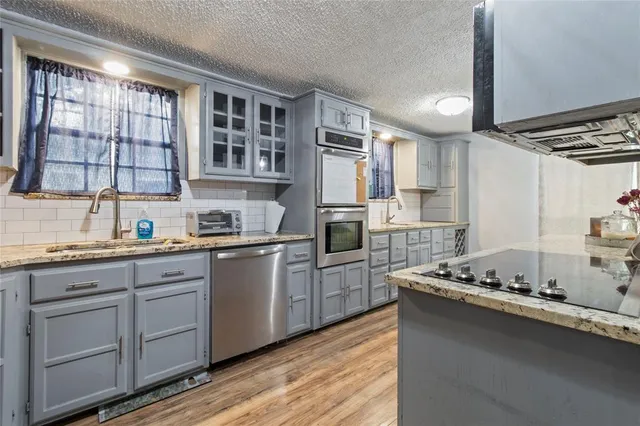 a kitchen with granite countertop cabinets stainless steel appliances a sink and a window