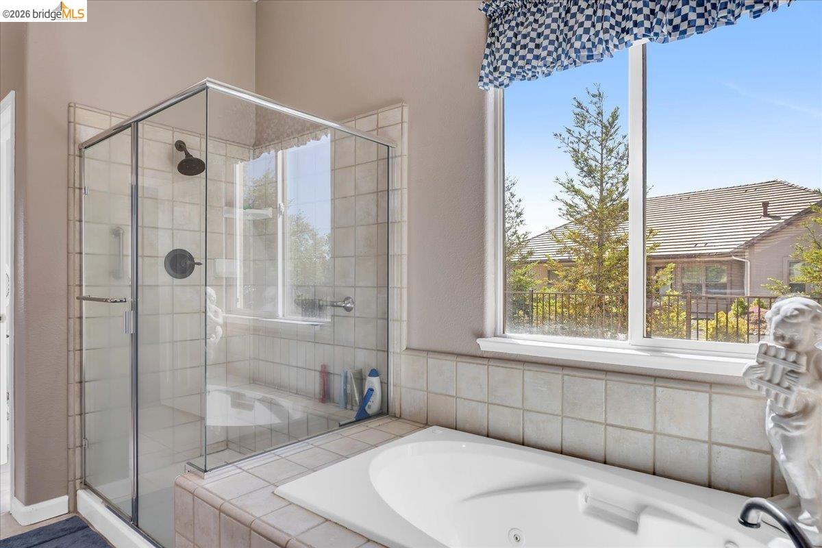 158 Rock Ridge Lane Copperopolis, CA 95228 - Photo 37 of 72 Glass-enclosed shower with dark bronze fixtures, integrated into a tiled surround that extends to a built-in jetted tub
