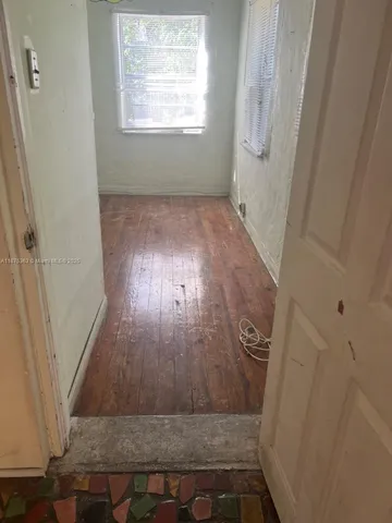 a view of a hallway with wooden floor and a bathroom