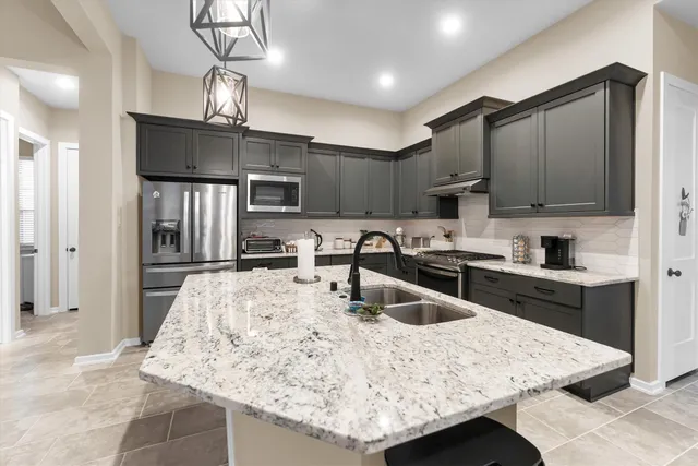 a kitchen with stainless steel appliances granite countertop a sink refrigerator and cabinets