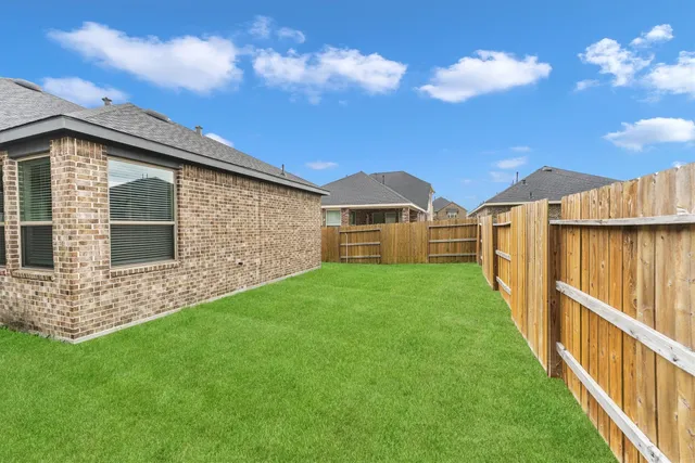a view of a backyard with couches plants and large trees