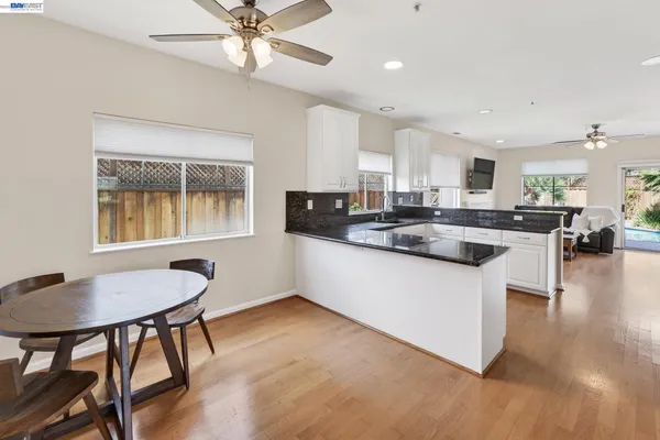 a kitchen with stainless steel appliances granite countertop a stove a sink a microwave a dining table and chairs with wooden floor