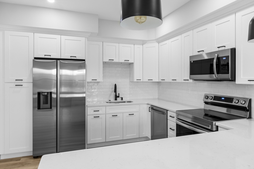 889-895 Grinnell Street, Unit 2 Fall River, MA 02721 - Photo 14 of 42 a kitchen with stainless steel appliances a refrigerator a stove a sink and white cabinets